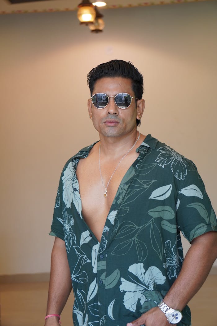 Home Man posing confidently indoors wearing a floral shirt and sunglasses - fashion statement.